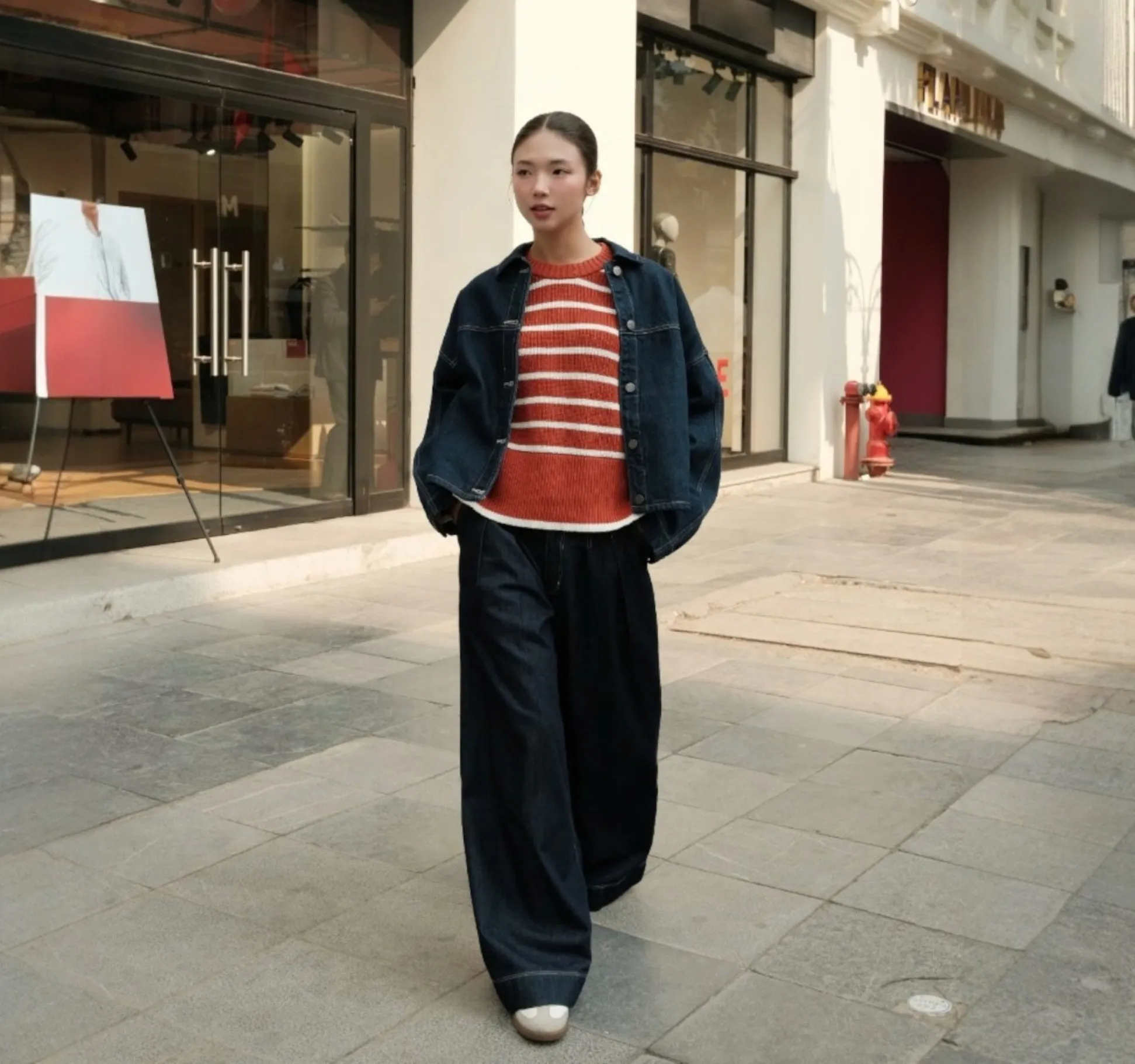 Áo len màu đỏ cam kết hợp cùng quần jeans tối màu và giày thể thao trắng, phù hợp cho người mệnh Thổ, mang lại cảm giác năng động, thanh lịch (Nguồn: Routine)